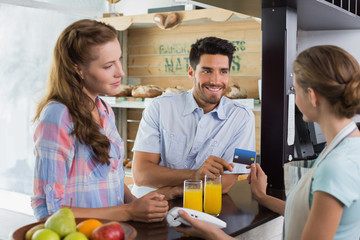 Fototapeta premium Couple paying bill at coffee shop using card bill