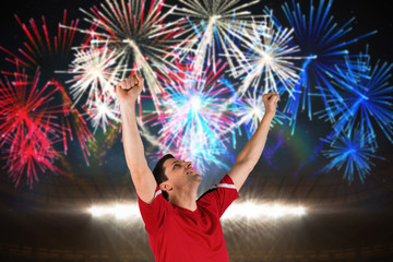 Excited football player cheering against fireworks exploding over football stadium