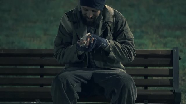 Lonely homeless in the park at night,counting his money to buy something to eat