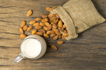almonds milk with almonds in sackcloth on wooden