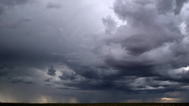 Time-lapse storm clouds driven by cross-currents as rain falls on horizon