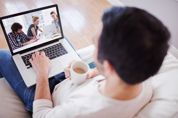 High angle view of young man using his laptop against casual business people around conference table in office