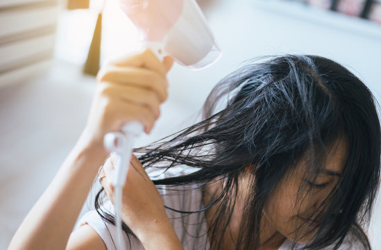 Young asian woman after bath hairbrushing her hair with comb,Female drying her long hair with dryer,Close-up