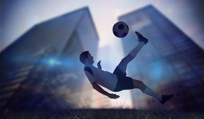 Fototapeta na wymiar Football player in white kicking against low angle view of skyscrapers