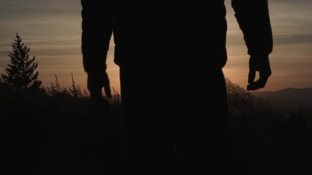 From black, transition to reveal person walking down grassy field in Oregon during sunrise, slow motion.
