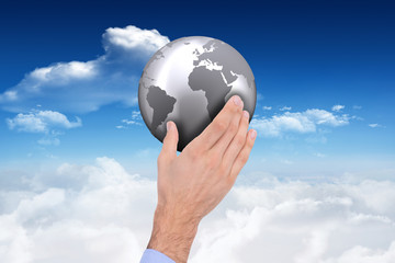 Businessman holding hand out in presentation against bright blue sky with clouds