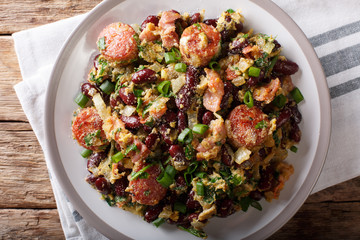 Brazilian beans with greens, sausages, bacon and eggs close-up on a plate. horizontal top view