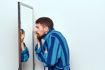man in bathrobe looking in the mirror