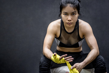 Asian female boxer wearing yellow strap on wrist. Beautiful young woman with muscular body preparing for boxing - Powered by Adobe