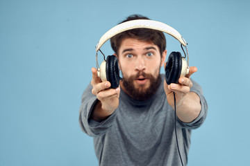 man surprised with outstretched headphones on a blue background