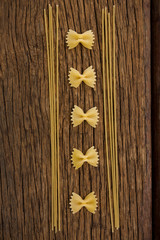 Farfalle and spaghetti on wooden surface