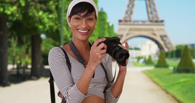 Young African-American photographer in Paris, France turns to take photo of viewer, Attractive young female artist taking photos outside near Eiffel Tower, 4k