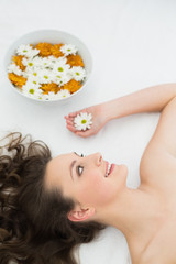 Obraz na płótnie Canvas Beautiful woman lying with bowl of flowers in beauty salon