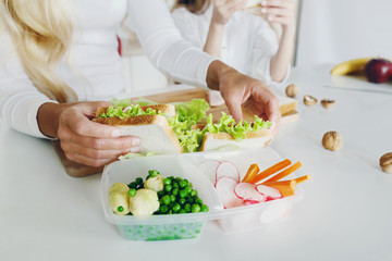 Obraz na płótnie Canvas Mother preparing sandwich school lunch table close up