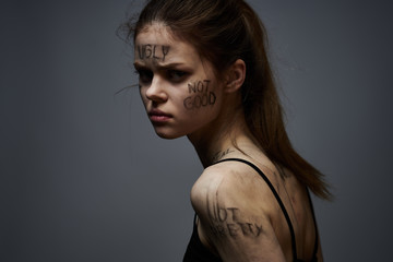 woman with inscriptions on her face and on her skin on a gray background