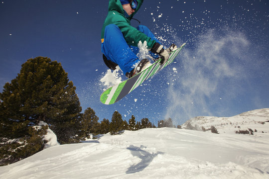 Snowboarder jumping through air in winter forest and snow