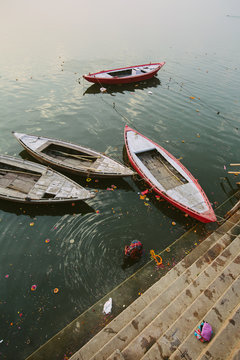 Old boats and woman swimming in Ganga river, Varanasi, India