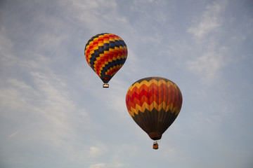 Isolated Skyward View of Hot Air Balloons Against Wispy Clouds in Blue Sky 