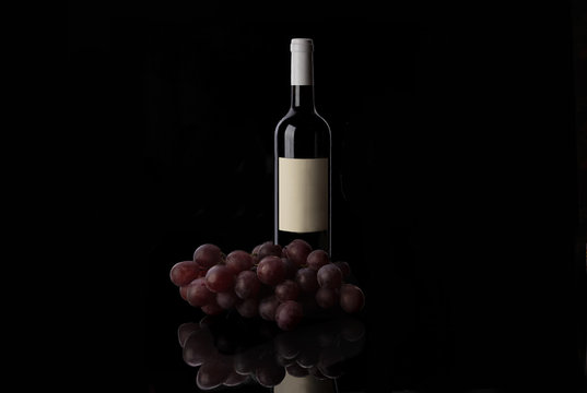 Red wine bottle and grape on black background