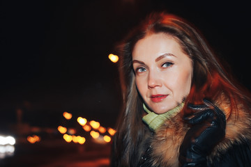 Naklejka premium Portrait of a nice girl in a warm coat in a dark city