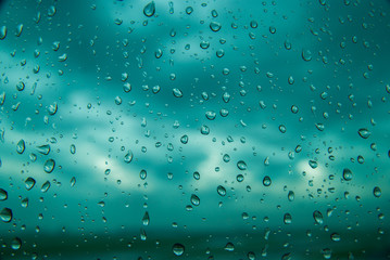 Naklejka na ściany i meble Blue water drops on window glass after rain. Cloud Background