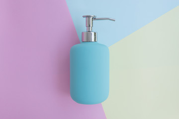 Fototapeta premium Minimal flat lay concept of blue shower gel, shampoo or cosmetic bottle on the colorful background with copy space