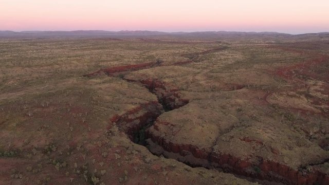 Aerial view of canyon gorge cutting through the desert landscape in Karijini NP Australia at sunrise.