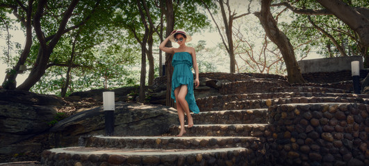 A girl in a turquoise dress is walking along the steps. Walk in the park.