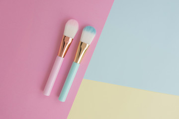 Minimal flat lay of creative female decorative cosmetic for pink and blue cheek brush on the colorful background with copy space