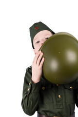 boy in uniform, peeking out from behind a green helmet, isolated on white