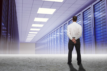 Businessman turning his back to camera against server hallway in desert setting