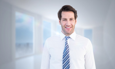 Smiling businessman standing with hands in pockets against bright white hall with columns