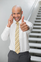 Businessman using cellphone and gesturing thumbs up