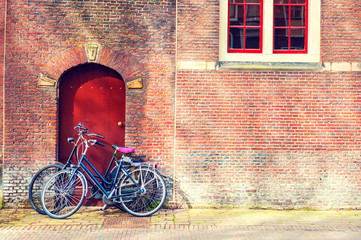Two bicycles near the red brick wall.
