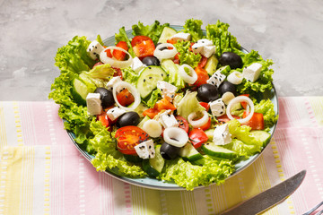 Traditional greek salad with fresh vegetables, feta cheese and olives on concrete background.