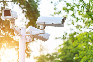 Security CCTV camera installed in the park at public area on blur background