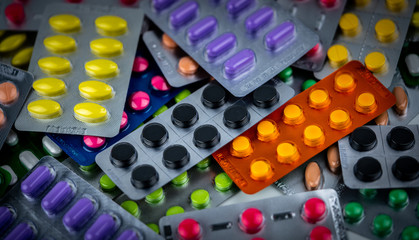 Pile of Colorful tablets pill in blister packaging. Pharmaceutical industry concept. Pharmacy drugstore. Pain killer and drug interaction with charcoal concept.