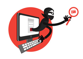 Hacker using a laptop and holding a credit card in front of computer