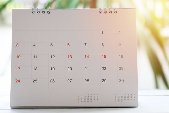 calendar is placed on a wooden floor on blur garden background.