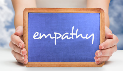 The word empathy and hands showing chalkboard against bright blue sky with clouds