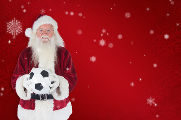 Santa holds a classic football  against red snowflake background