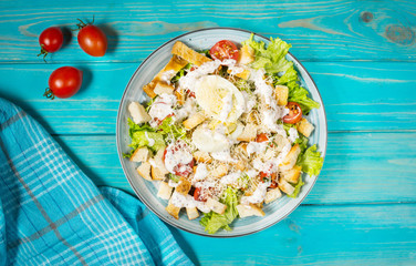 Fresh caesar salad in plate on blue wooden table. Top