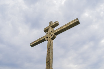 A wooden cross on top of a hill. Orthodox white cross glows on the top of the hill on the background of blue sky