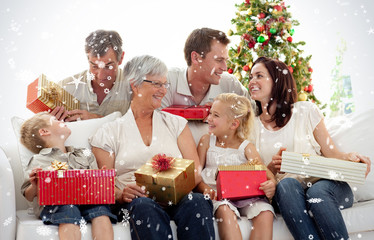 Composite image of Family giving presents for Christmas against snow falling