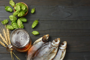 Glass beer with hop cones and dried fish on dark wooden background. Beer brewery concept. Beer background. top view