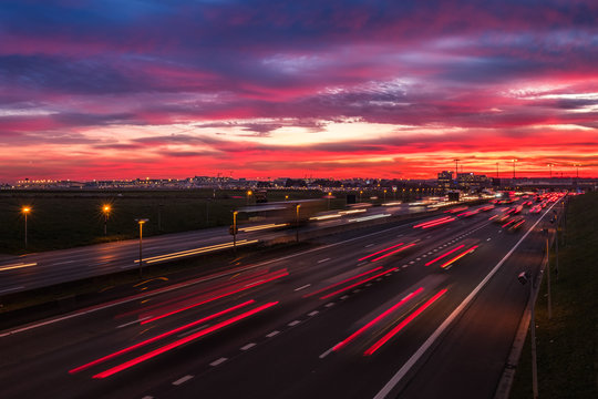Dramatic sky at dawn with cars lights trails near the international airport of Brussels, Belgium