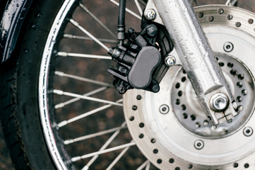 Motorcycle wheel with disk brakes system and metal spokes. Closeup detailed photo of motorbike forks and tire. Different parts of two-wheeled vehicle.  Transportation. Modern driving technologies.