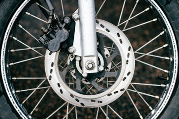 Obraz premium Motorcycle wheel with disk brakes system and metal spokes. Closeup detailed photo of motorbike forks and tire. Different parts of two-wheeled vehicle. Transportation. Modern driving technologies.