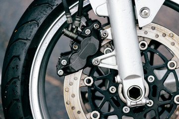 Obraz premium Motorcycle wheel with disk brakes system and metal spokes. Closeup detailed photo of motorbike forks and tire. Different parts of two-wheeled vehicle. Transportation. Modern driving technologies.