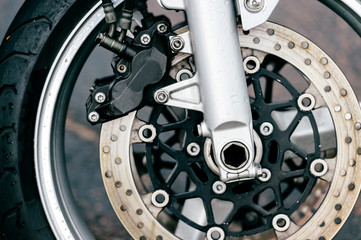 Motorcycle wheel with disk brakes system and metal spokes. Closeup detailed photo of motorbike forks and tire. Different parts of two-wheeled vehicle.  Transportation. Modern driving technologies.